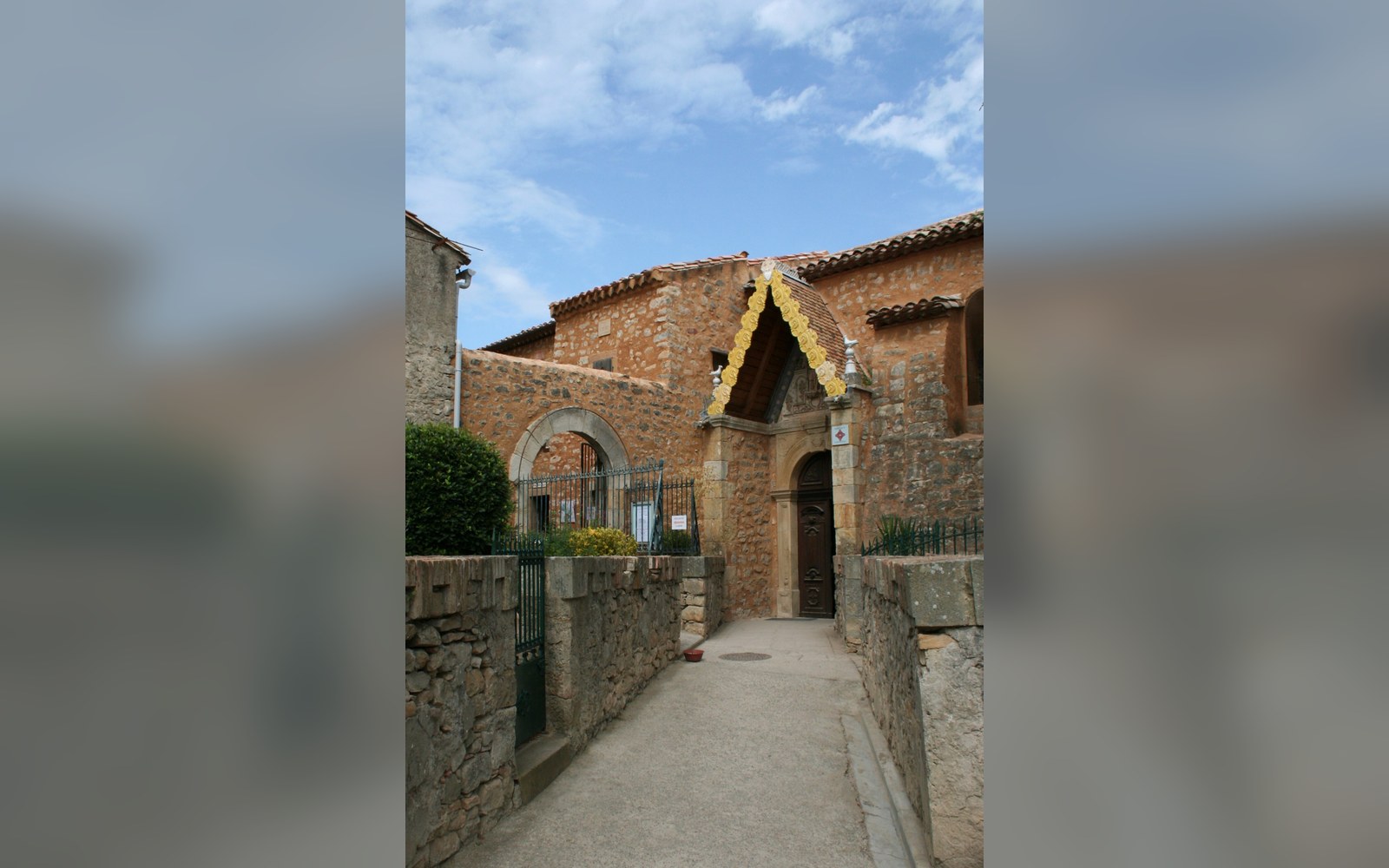 Stone church entrance with an arched wooden door and decorative gable trim above it