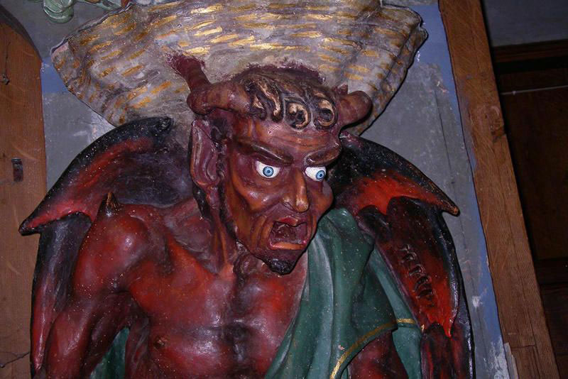 devil holding and supporting the holy water vessel
